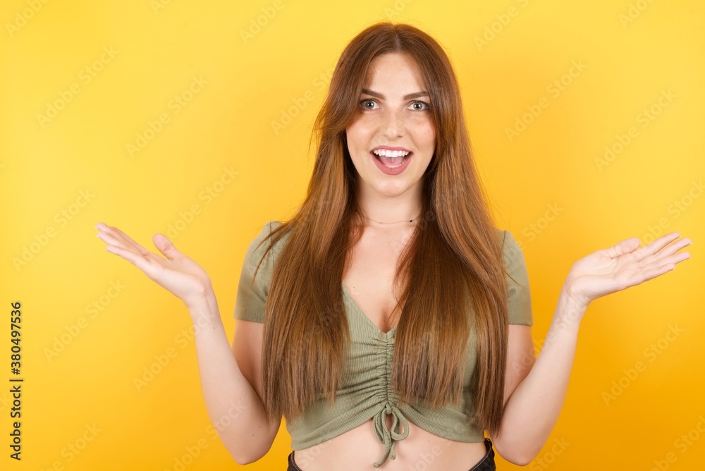 Young caucasian woman with long hair wearing green tshirt standing over isolated yellow wall celebrating crazy and amazed for success with arms raised and open eyes screaming excited. Winner concept Young caucasian woman with long hair wearing green tshirt standing over isolated yellow wall celebrating crazy and amazed for success with arms raised and open eyes screaming excited. Winner concept