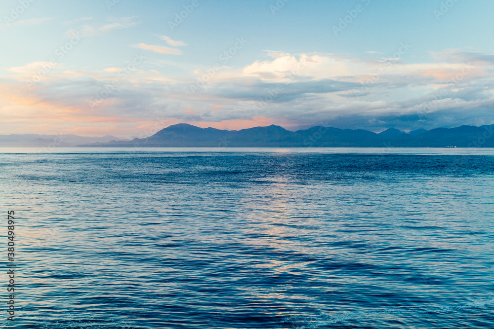Scenic sunset over a strait with mountains in the background