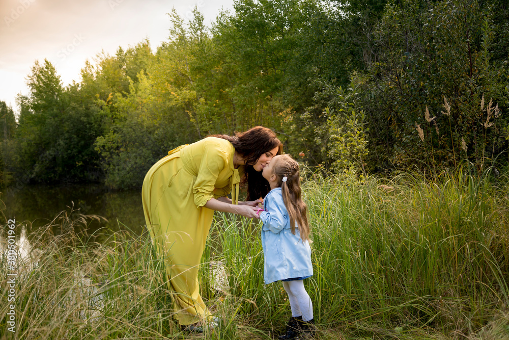 Pregnant woman in yellow dress with her daughter in nature Pregnant woman in yellow dress with her daughter in nature
