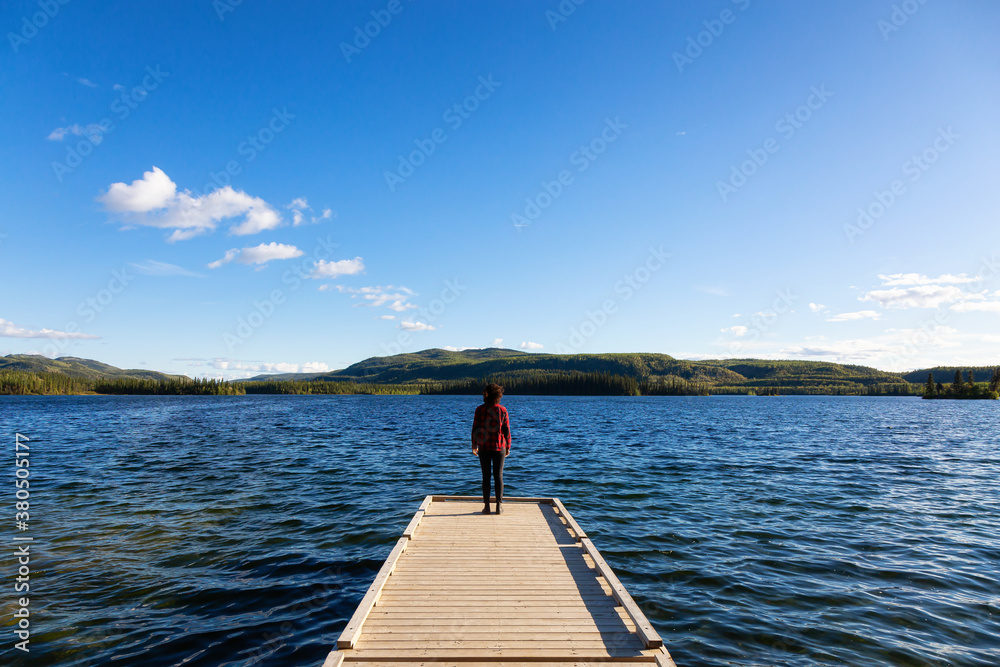 Adventurous Girl on a Wooden Quay at Twin Lakes Campground during a sunny summer day. North of Whitehorse, Yukon, Canada. Concept: travel, adventure, freedom