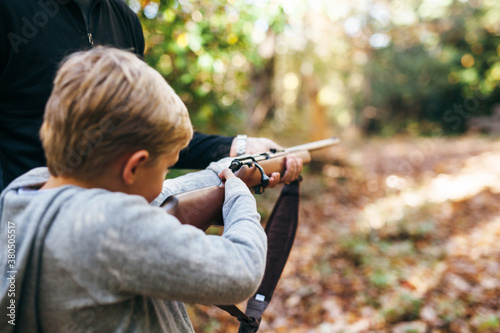 father and son shooting a rifle in the forest