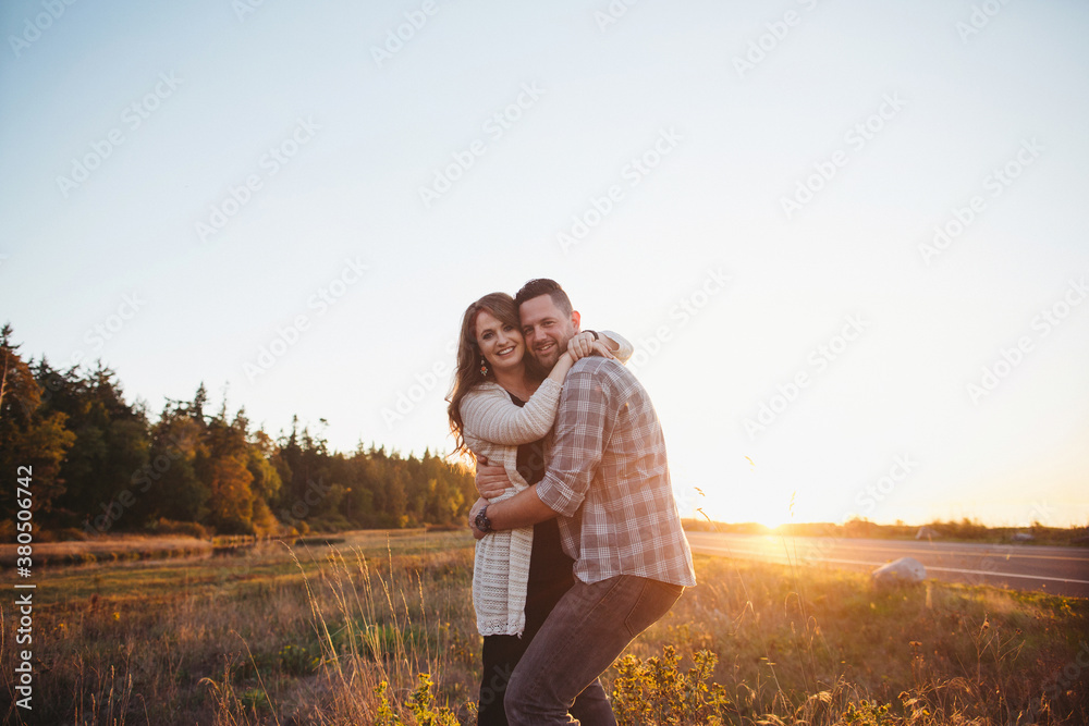 Happy couple enjoying life together at sunset - looking at camera Happy couple enjoying life together at sunset - looking at camera