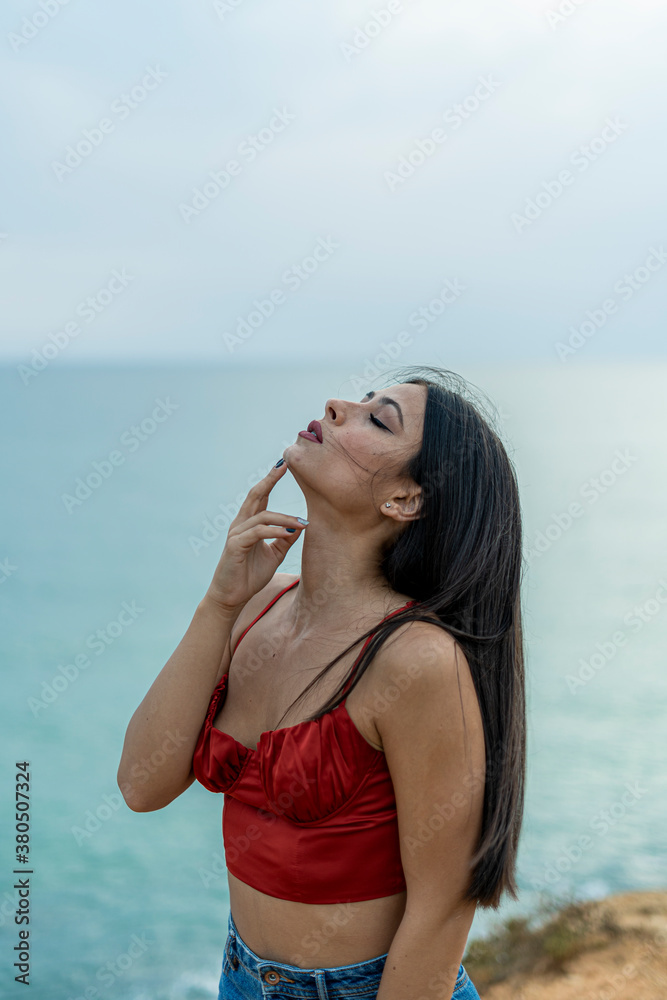 Mujer joven adolescente modelo posando en un acantilado y en la playa. Chica vestida elegante para modelo Mujer joven adolescente modelo posando en un acantilado y en la playa. Chica vestida elegante para modelo