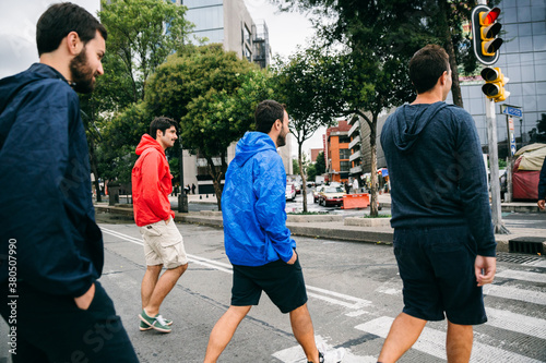 Four young men friends cross a street on a zebra crossing photo