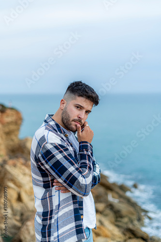Hombre joven adolescente modelo con camisa azul de cuadros posando en la costa y playa  © victor rangel