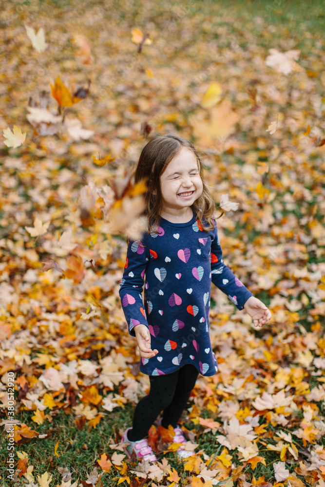 Cute young girl playing with leaves outside Cute young girl playing with leaves outside