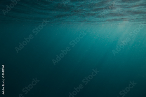 Dark blue under water empty sea background with sunrays going trough the surface