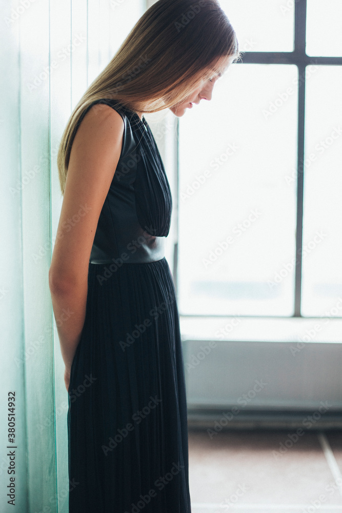 Beautiful woman in a dress leaning on glass wall Beautiful woman in a dress leaning on glass wall