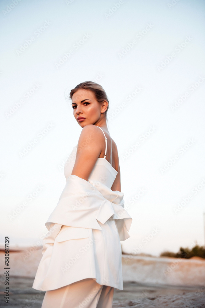 Woman in white suit having photo session in sand quarry Woman in white suit having photo session in sand quarry
