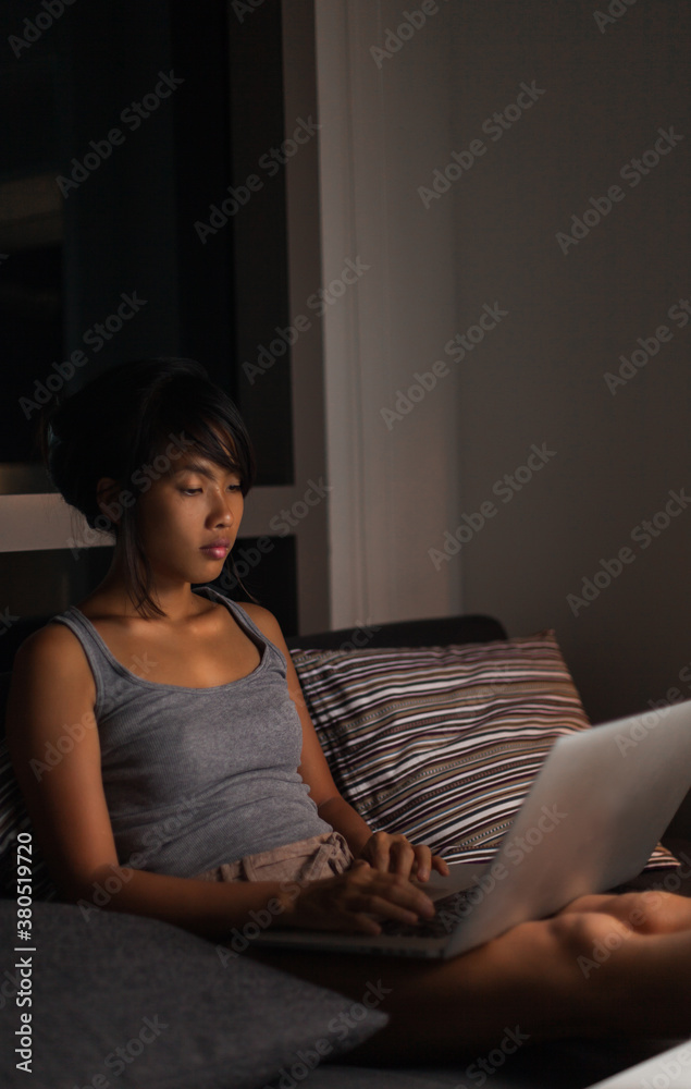 Beautiful asian woman using her laptop in her home during evening. Beautiful asian woman using her laptop in her home during evening.