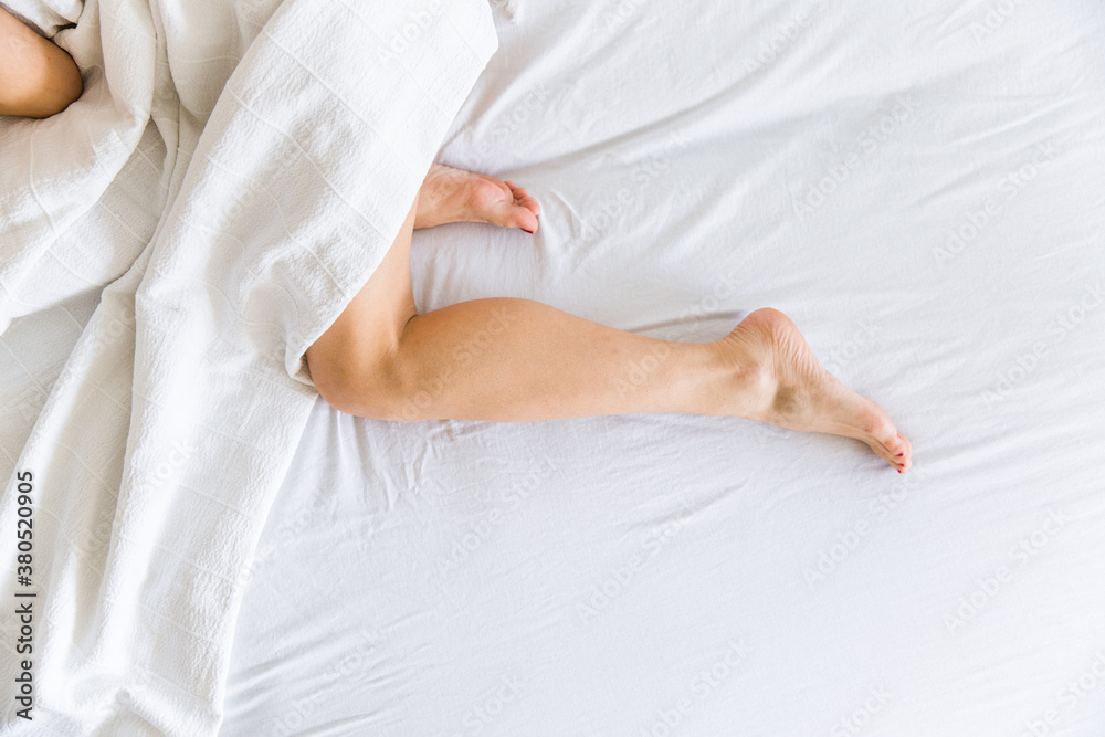 Woman legs on the bed in white bedclothes Woman legs on the bed in white bedclothes