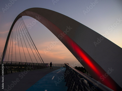 Teenager is riding his scooter on "Tolerance bridge" structure in Dubai. "Dubai water canal", UAE.