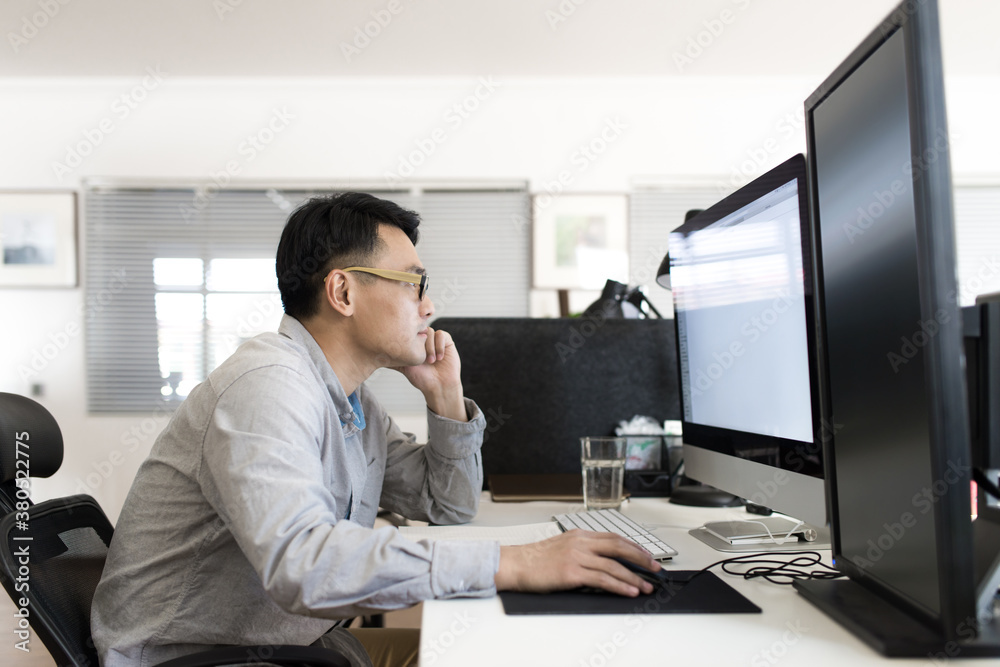Man sitting on his desk and working on a computer Man sitting on his desk and working on a computer