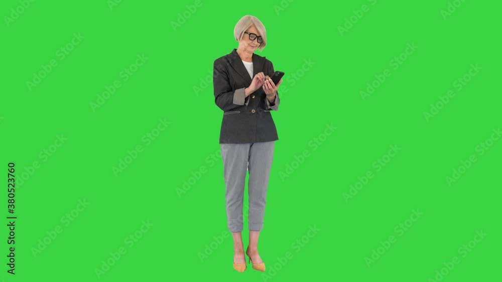 Elderly business woman works on a smartphone on a Green Screen, Chroma Key. Elderly business woman works on a smartphone on a Green Screen, Chroma Key.