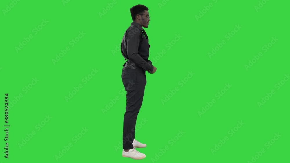 Young African American businessman in glasses standing and pulling down his waistcoat on a Green Screen, Chroma Key. Young African American businessman in glasses standing and pulling down his waistcoat on a Green Screen, Chroma Key.