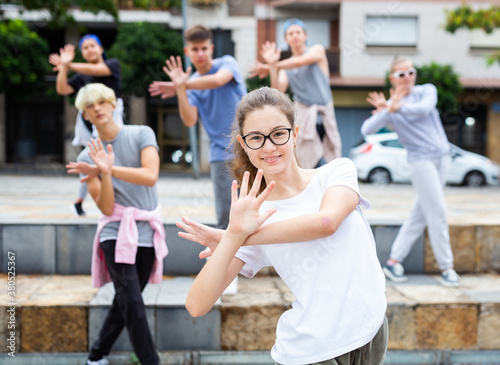 Portrait of emotional girl doing hip hop movements during group class at city street