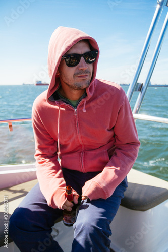 Young man wearing a hoddie sitting down in a sail boat on a cold clear sunny day photo