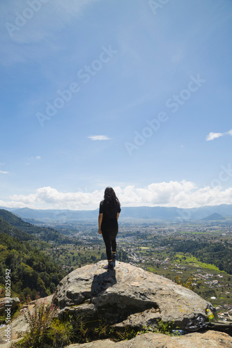 Young woman sitting on top of the mountain enjoying nature- woman on the edge of the cliff observing the valley enjoying a day outdoors- landscape in Quetzaltenango Guatemala.