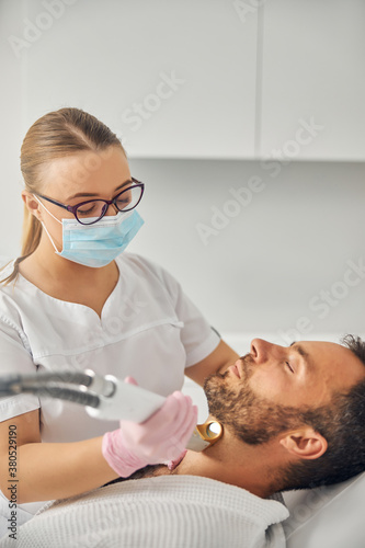 Female esthetician performing laser hair removal procedure