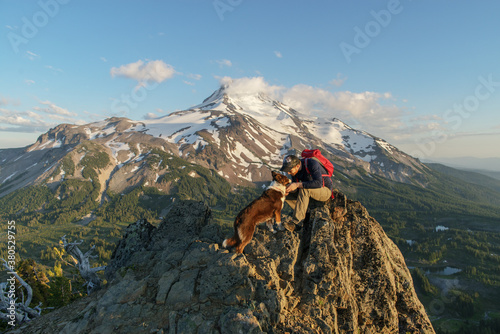 Man and dog high up at sunset with mountain behind them photo