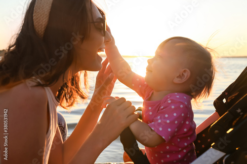 Fotografía Woman and her cute baby in stroller near river