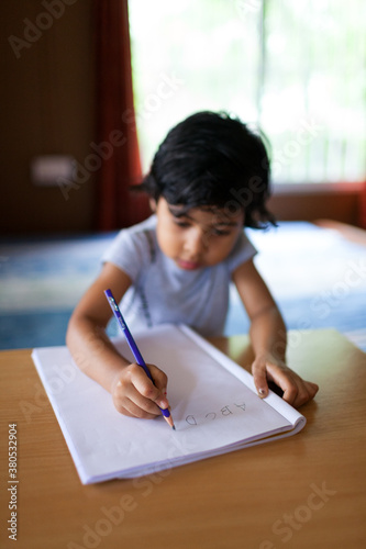 Little girl learning to write the english alphabets