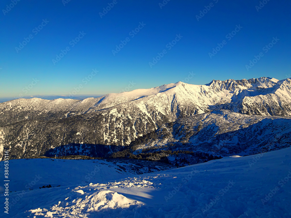 Beautiful winter landscape. Snow on the mountain with blue sky background. Wonderful sunset at height. Mount Carpathians in the Bansko region of Bulgaria.