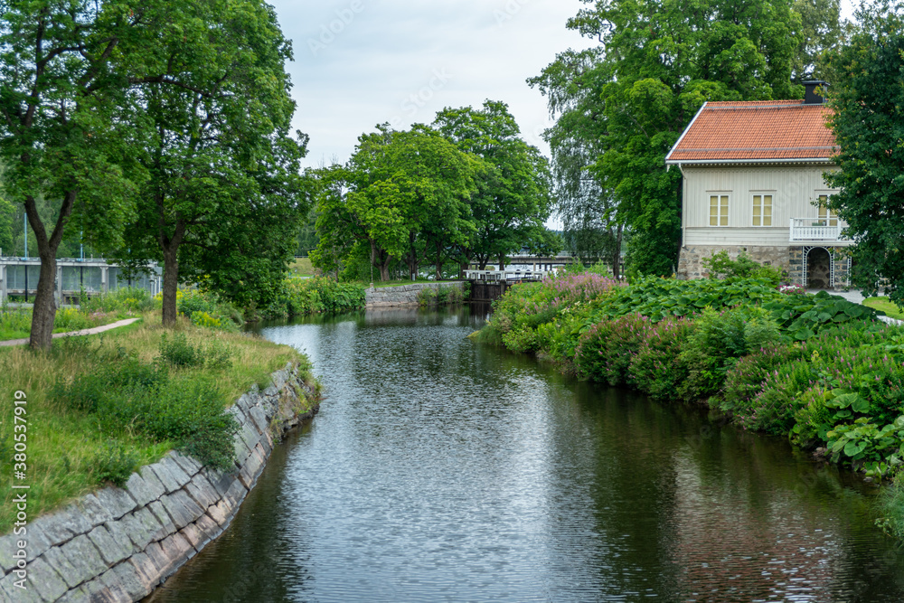 Lush green summer view of a sluice or lock gate at the stromsholms canal in Sweden Lush green summer view of a sluice or lock gate at the stromsholms canal in Sweden