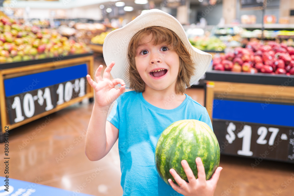 Fototapeta premium Portrait of child hold watermelon in grocery shopping in supermarket, Concept of shopping, healthy food, sell and buy.