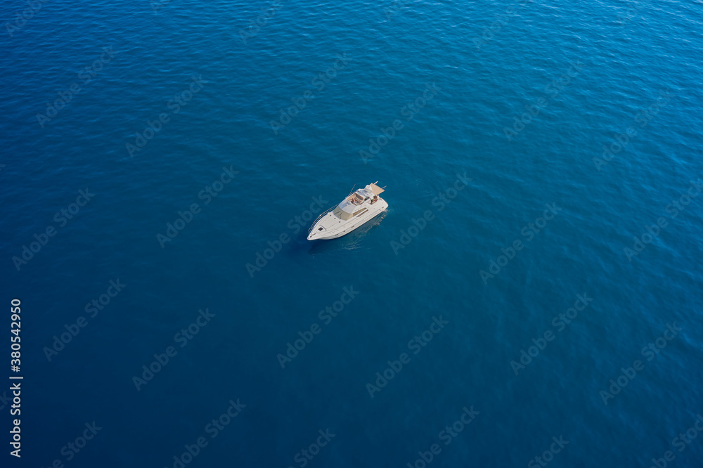 White big yacht anchored on blue water. Drone view of a boat  the blue clear waters. Aerial view luxury motor boat.