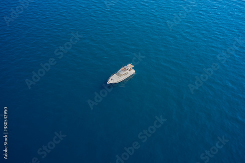 White big yacht anchored on blue water. Drone view of a boat the blue clear waters. Aerial view luxury motor boat.