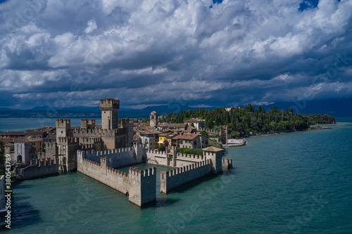 Aerial view on Sirmione sul Garda. Italy, Lombardy. Aerial photography with drone. Rocca Scaligera Castle in Sirmione. Cumulus clouds over the island of Sirmione.