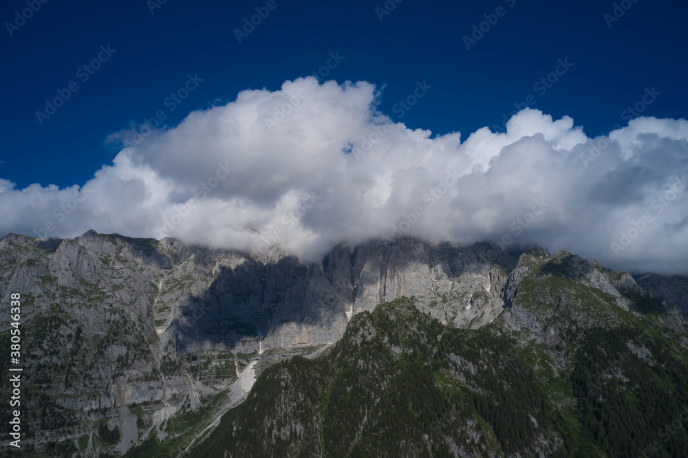 Panorama of beautiful countryside of Italy. High mountains in the Europe. Clouds at the top of the Alps. Idyllic landscape in the Alps.