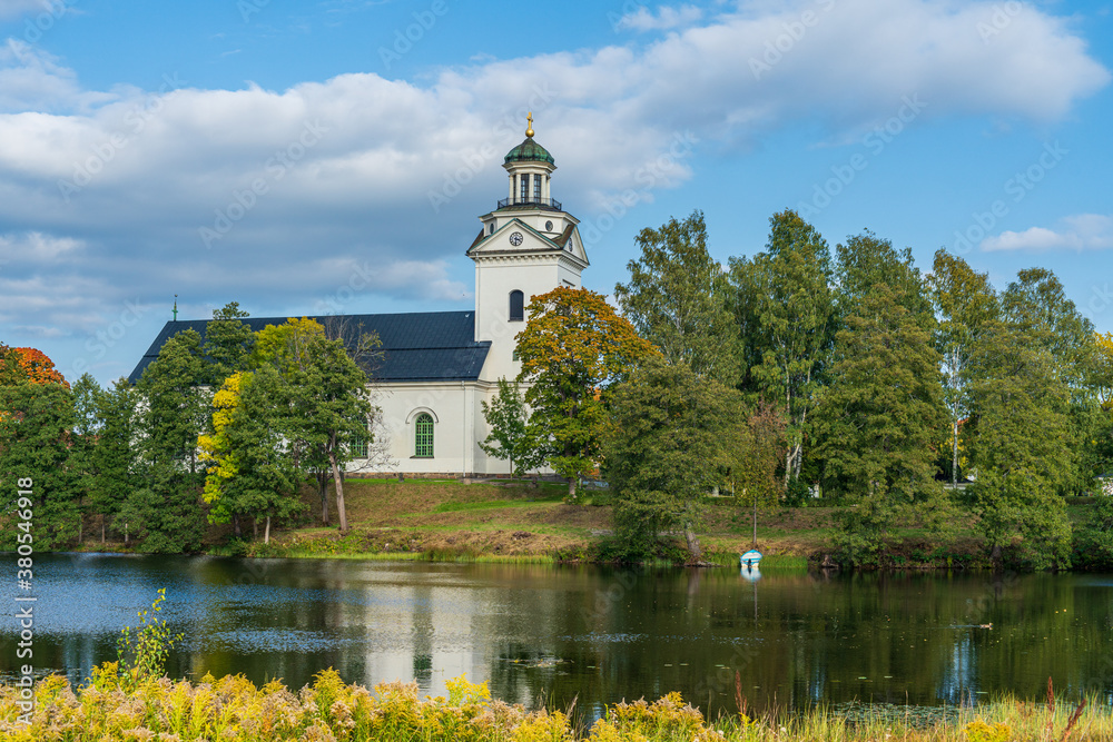 White church by the river, in sunlight and autumn colored trees