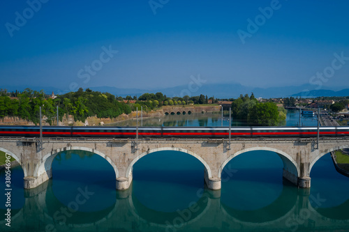 Train passing over the bridge that crosses the reservoir Blurred train movement on arch bridge over the river against the background of mountains.