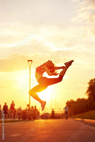 modern style dancer woman jumping. Dancer silhouette at sunset. Contour of girl on urban city background