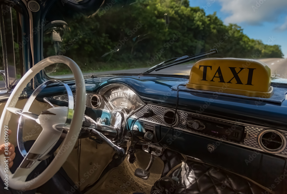 Fototapeta premium A Taxi driving on a Cuban road.