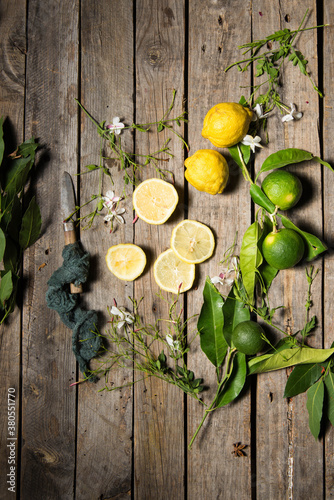 Lemons and limes on an old wood background with a vintage knife and some azahar flowers photo