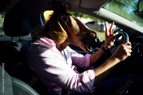 Man in disguise with a horse head driving the car