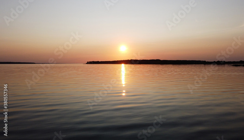 Beautiful sunset over a calm lake with reflection in the water © Payllik