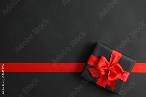 Gift box and red ribbon on black background