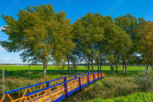 Bridge over a canal in a green grassy landscape in sunlight at fall, Almere, Flevoland, Netherlands, September 24, 2020 