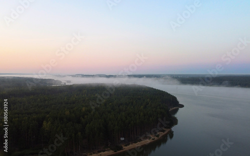 Top view of fog at sunrise over calm lake and forest