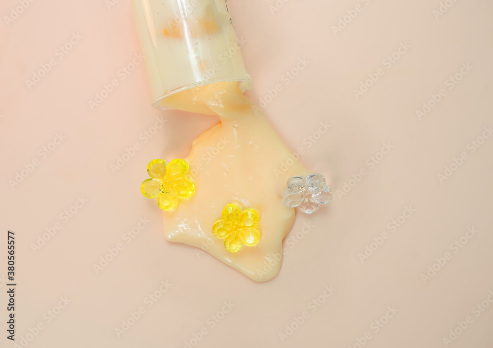 cream slime flows out of a can on a beige pink background with decorative glass flowers cream slime flows out of a can on a beige pink background with decorative glass flowers