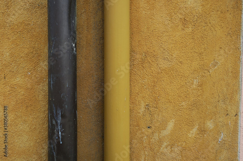 yellow ochre plastered wall with two drainpipes, brown and yellow photo