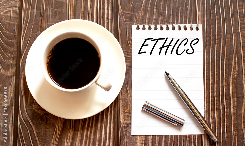 ETHICS - white paper with pen and coffee on wooden background