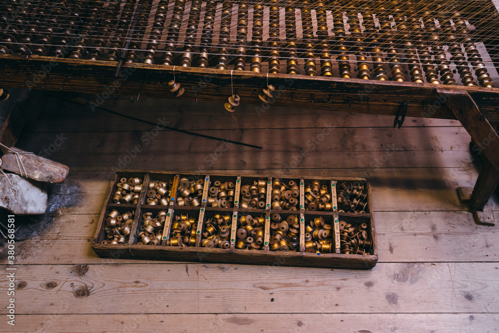 Wooden box with assortment of reels near the loom machine Wooden box with assortment of reels near the loom machine