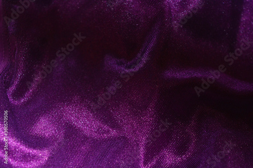 Bright colorful, rich velvet purple background with overflow and ebb. An unusual shaggy purple fabric with curves and waves is located on a flat surface, an unusual look.