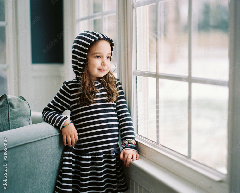 Cute young girl sitting in a chair looking out a window Stock Photo ...