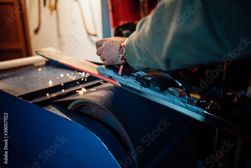 Man repairing a ski base on the emery paper machine